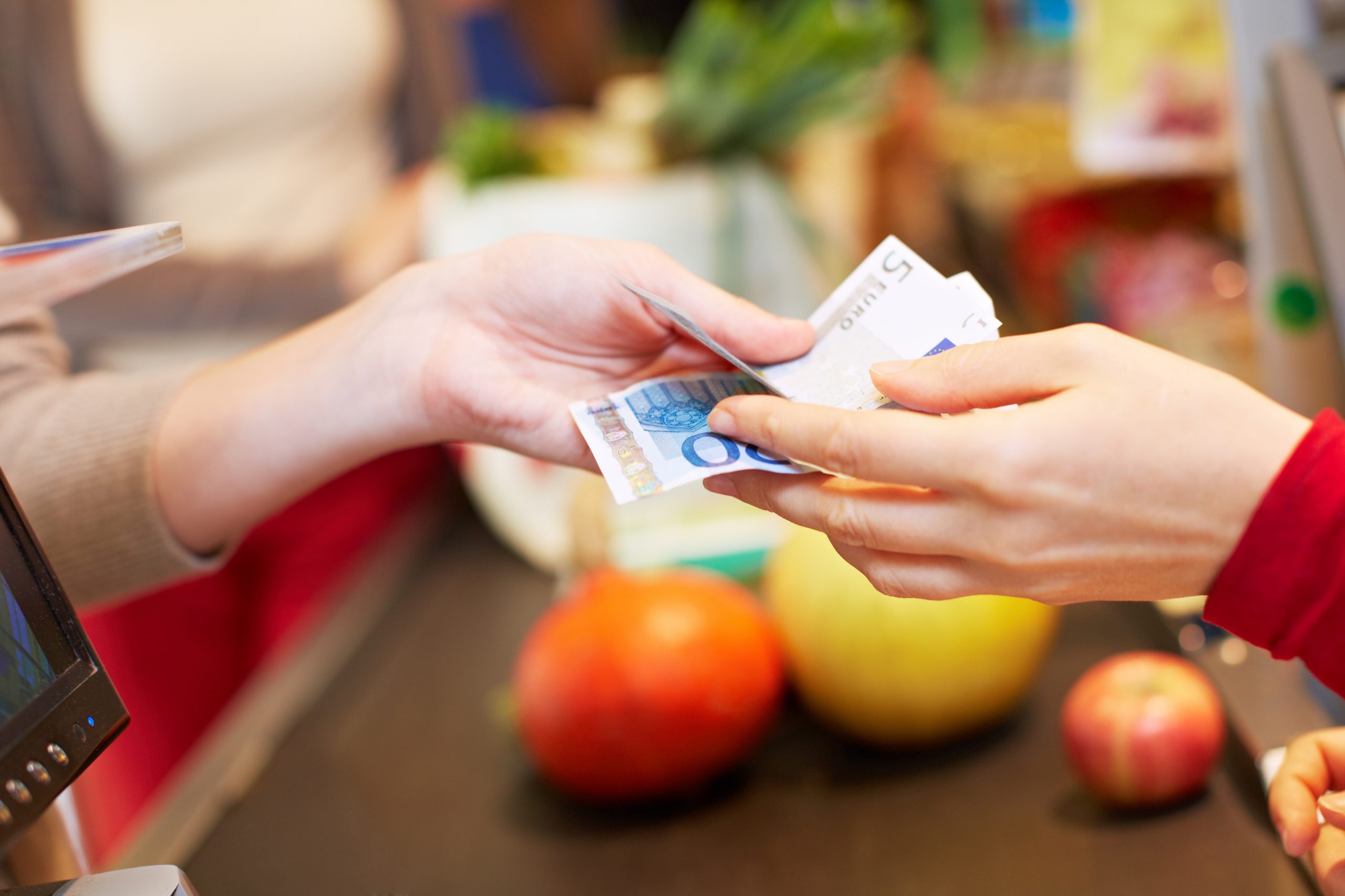 Hände übergeben Euroscheine an Kasse