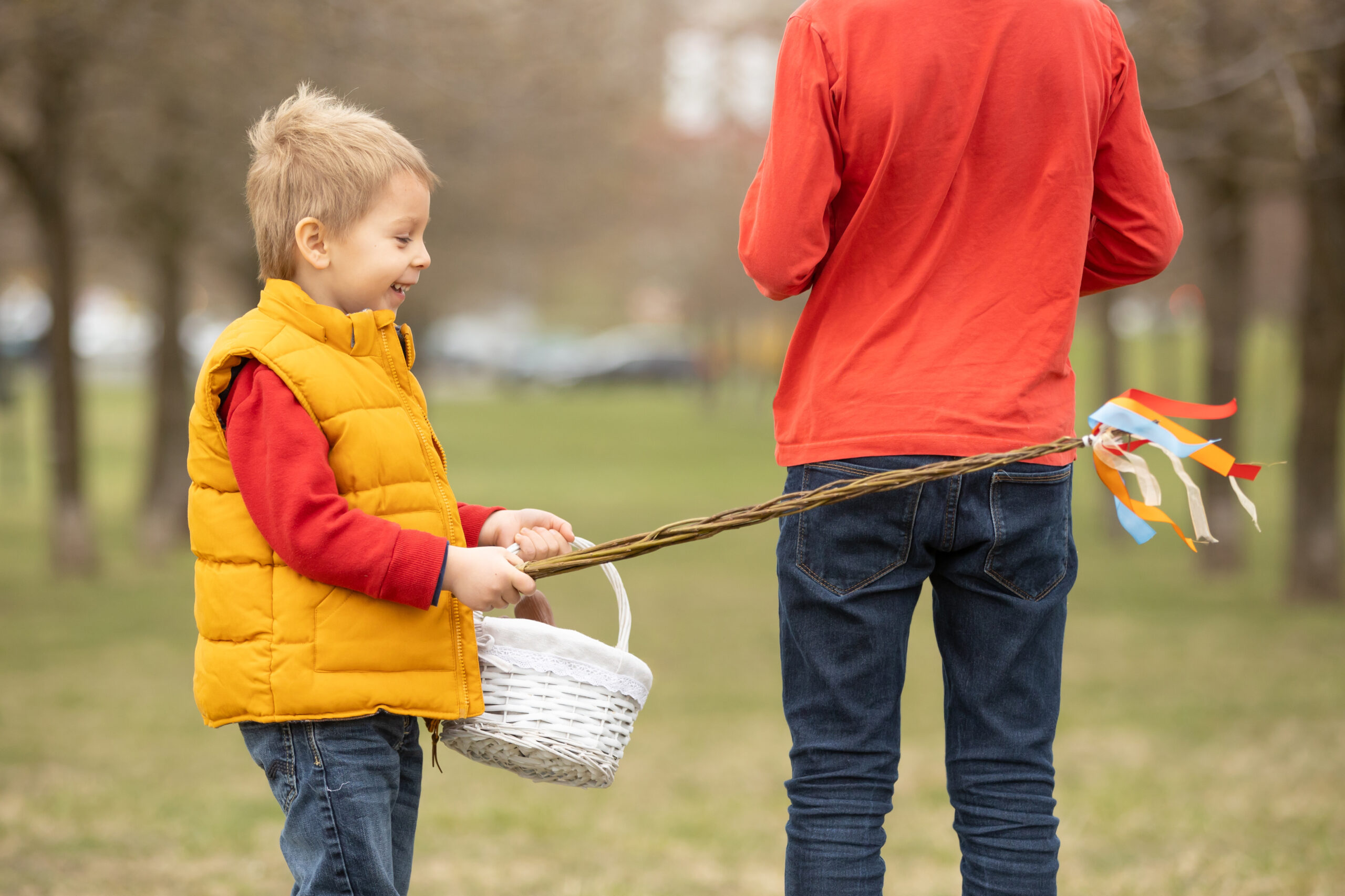Cute preschool child, whipping his sister on Easter with twig, b